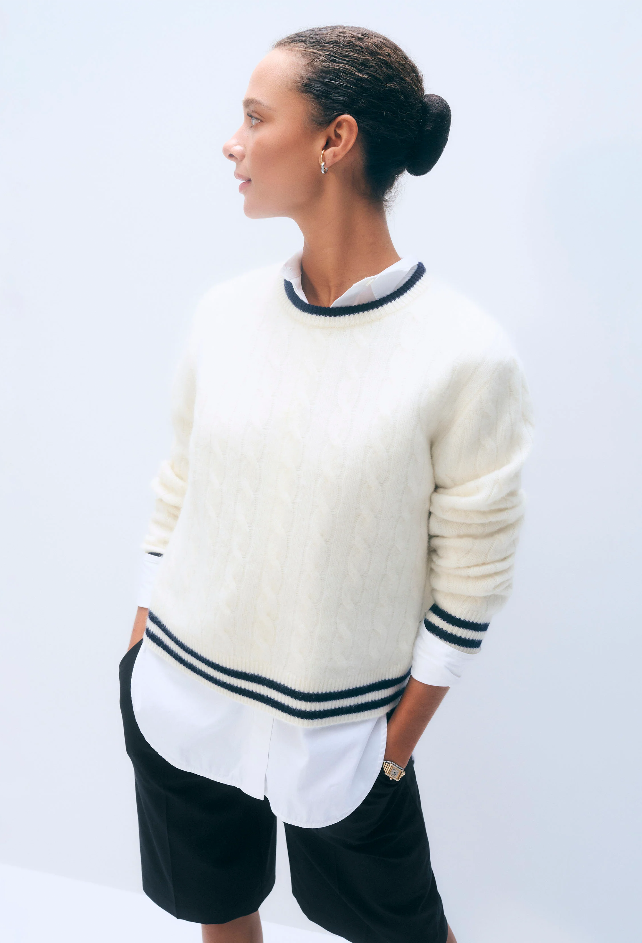 Person wearing a cream sweater with navy stripes on a white background