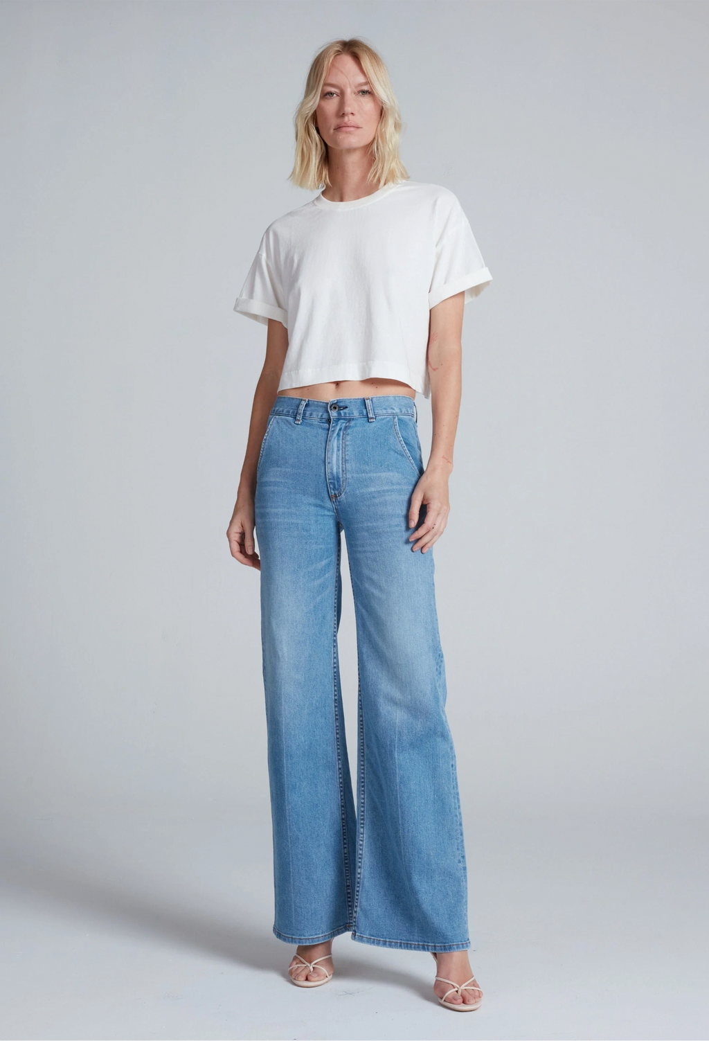 Woman wearing a white t-shirt and blue jeans on a gray background