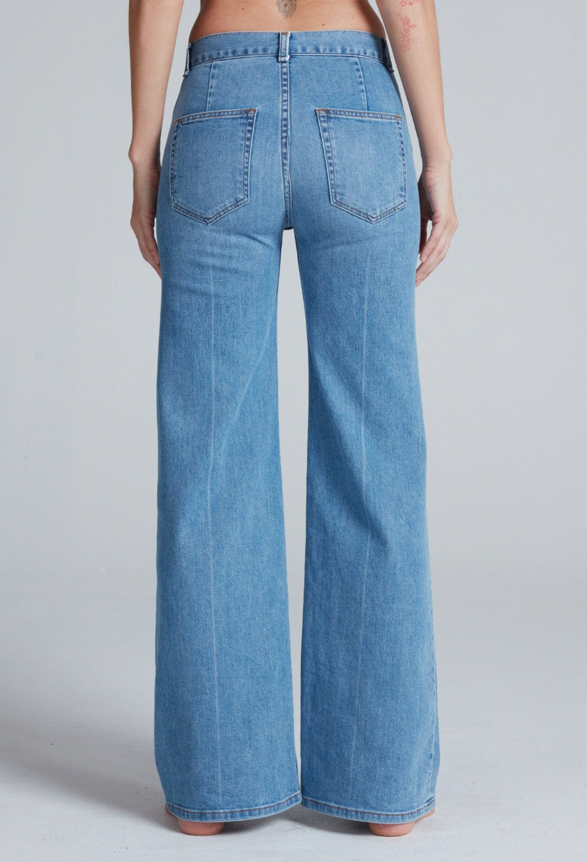 Blue jeans worn by a person on a gray background