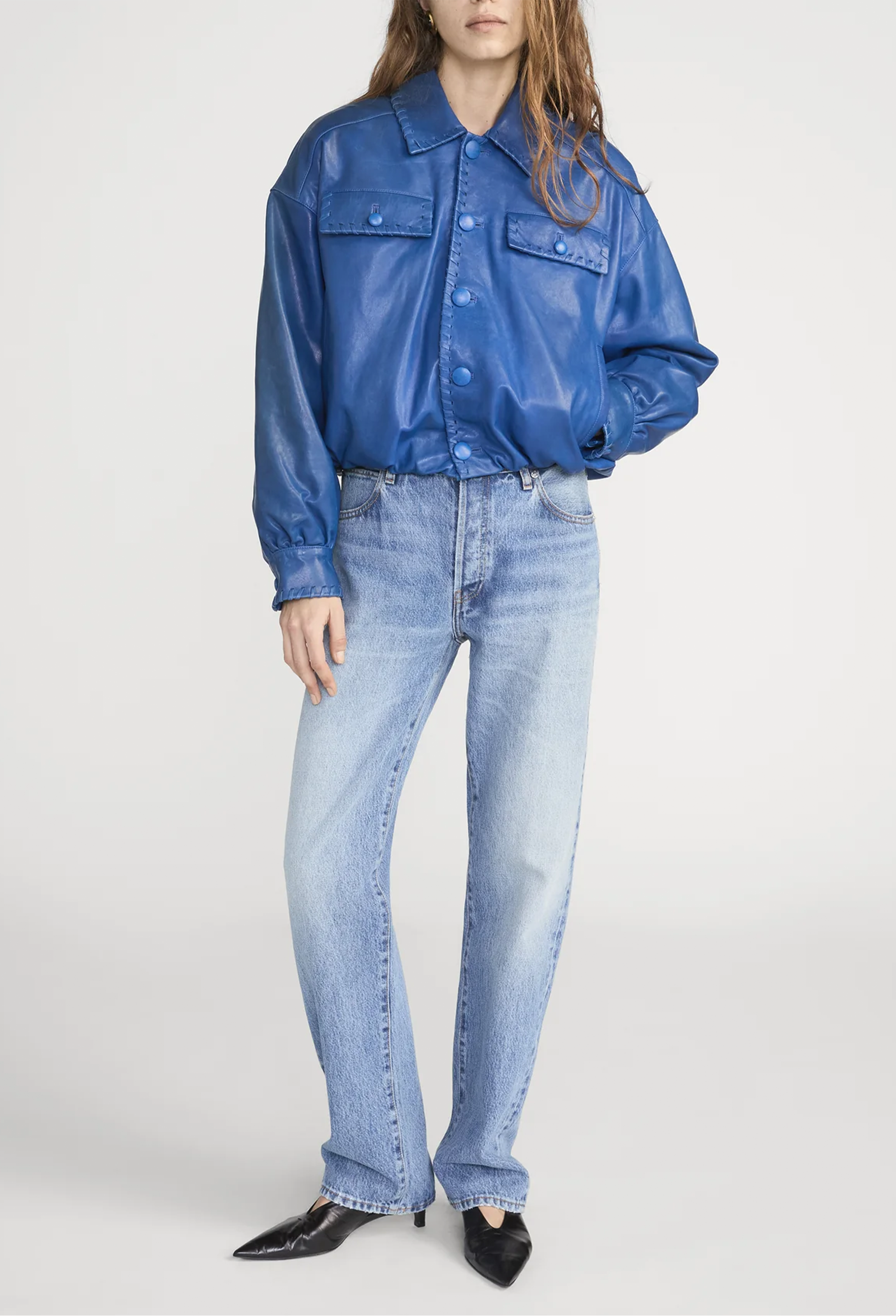 Person wearing a blue denim jacket and jeans on a white background