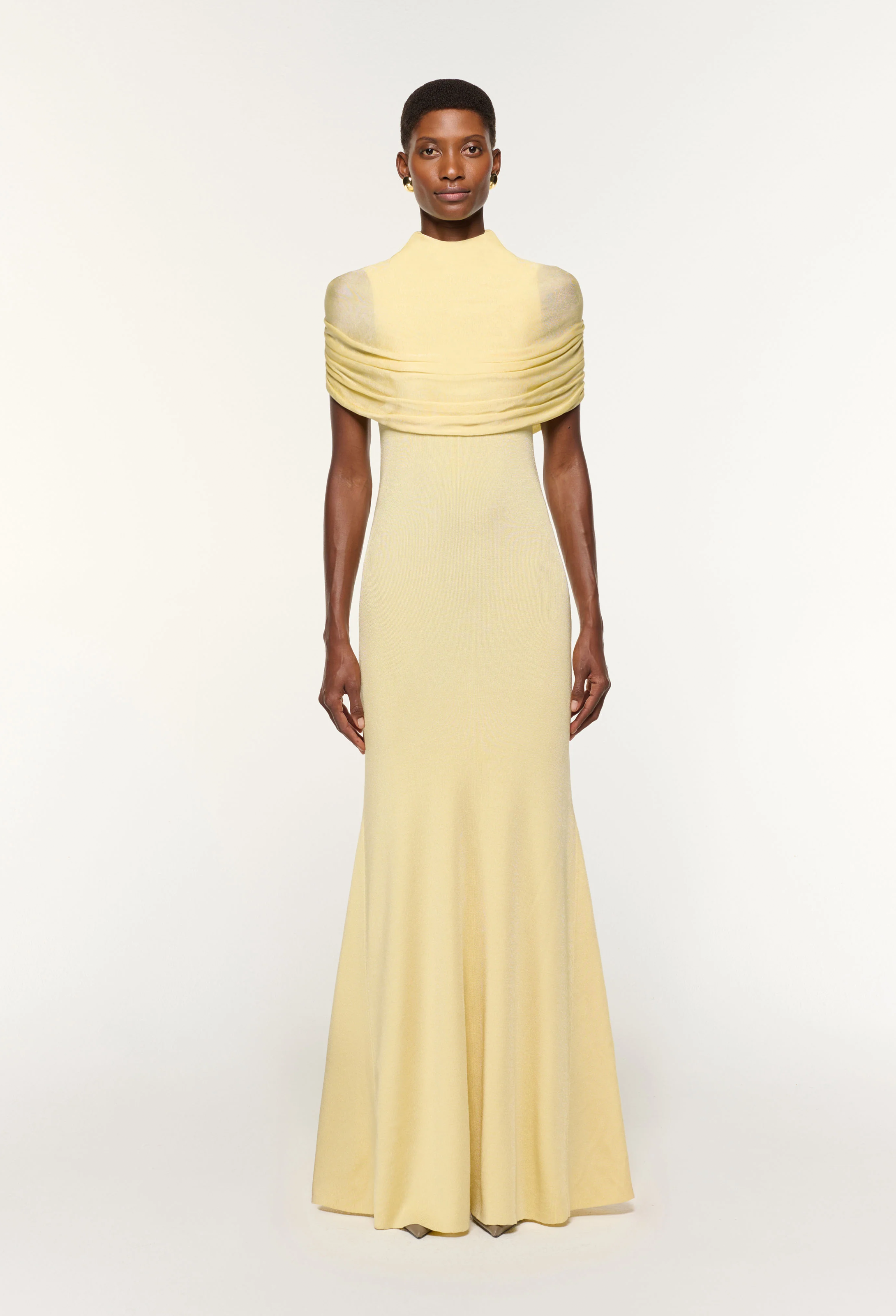Woman wearing a light yellow evening gown on a white background