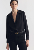 Woman wearing a black blouse and pants with a belt on a white background
