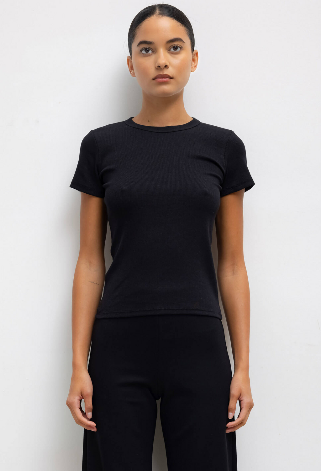 Person wearing a black t-shirt and pants against a white background
