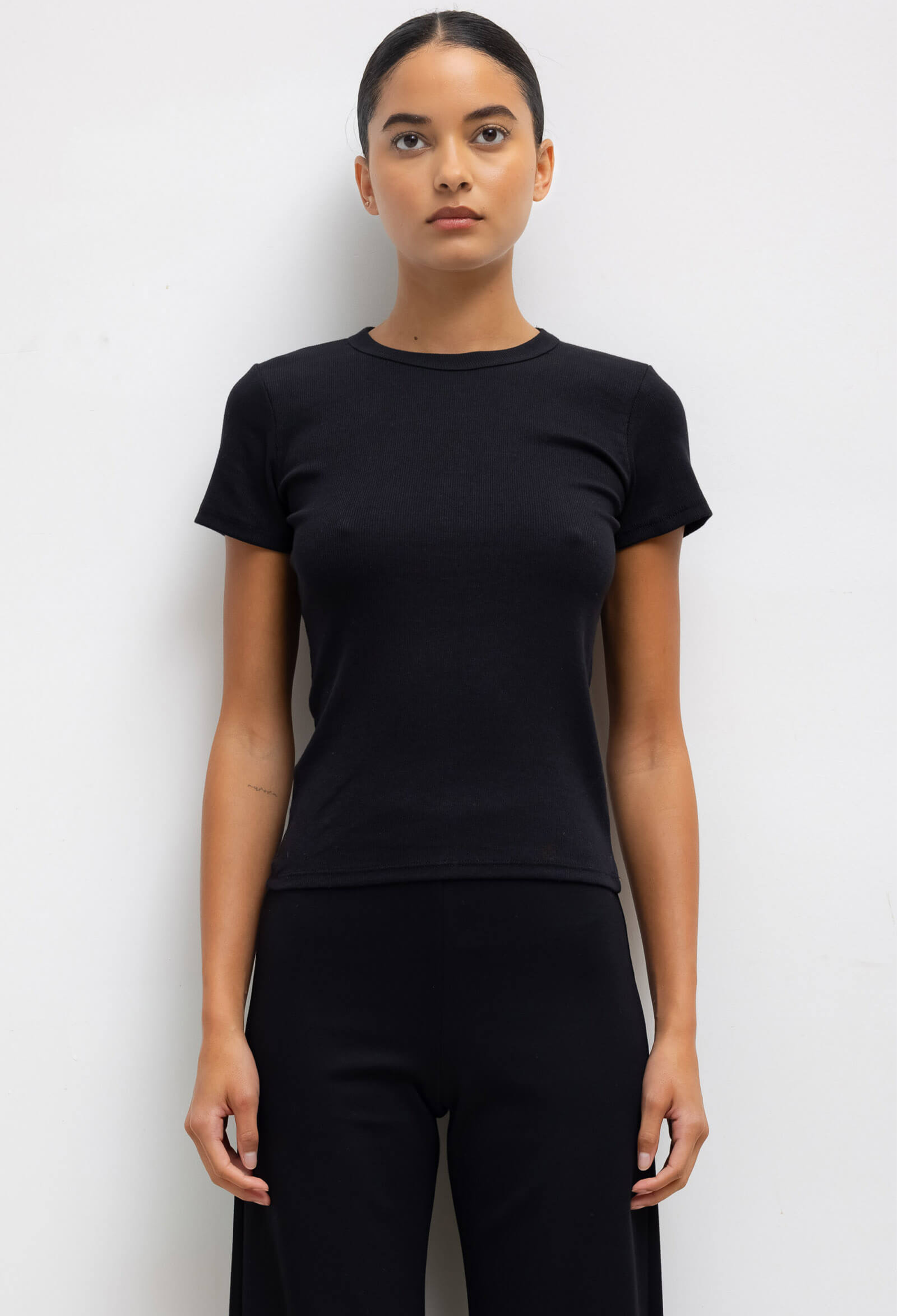 Person wearing a black t-shirt and pants against a white background