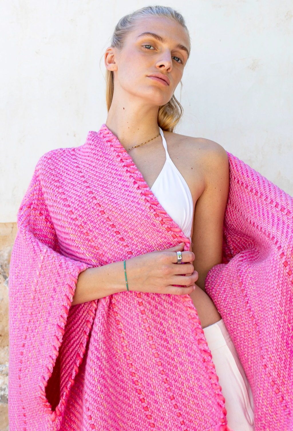 Woman wearing a pink knitted shawl over her shoulders against a white background
