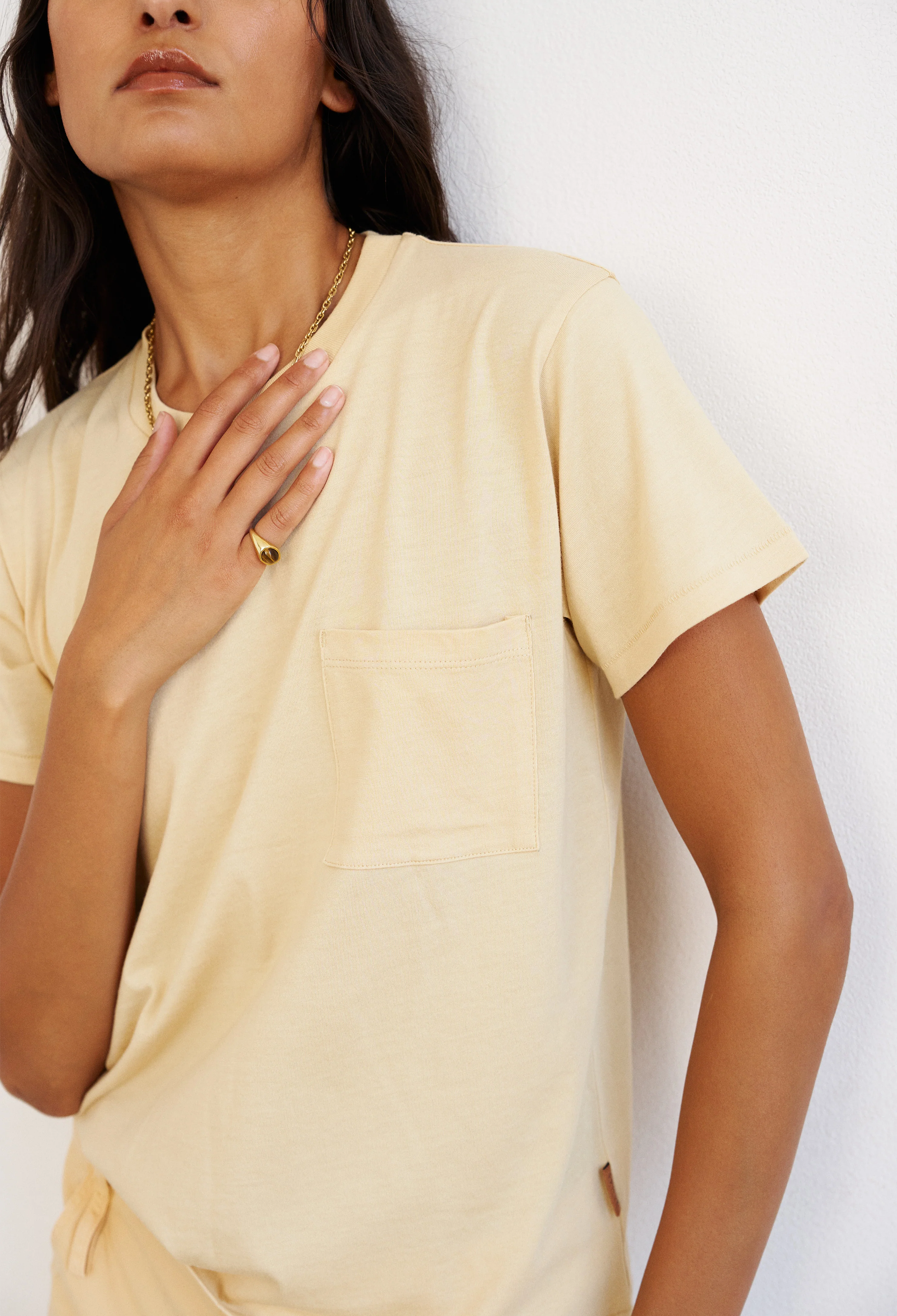 Woman wearing a light yellow top against a white background