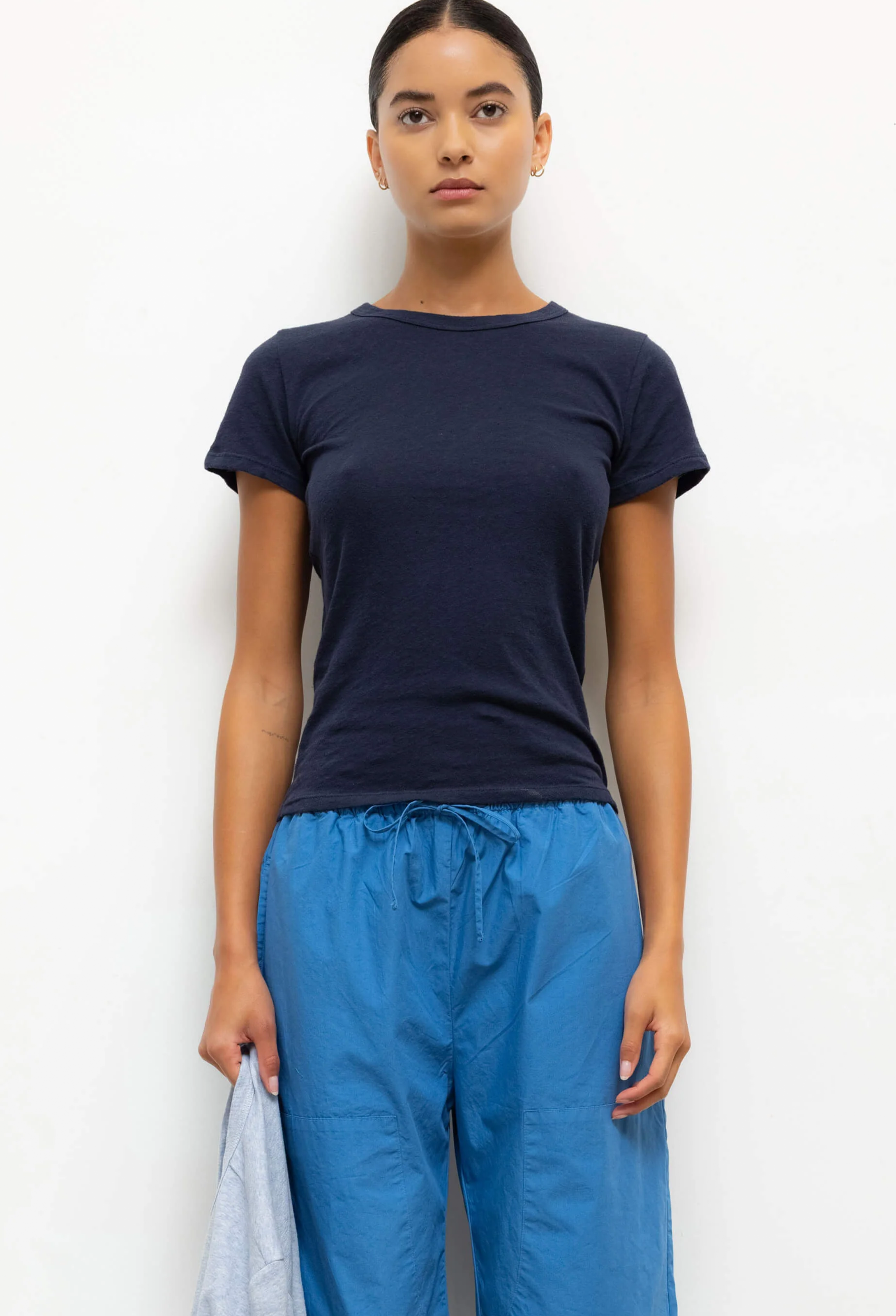 Person wearing a navy t-shirt and blue pants against a white background