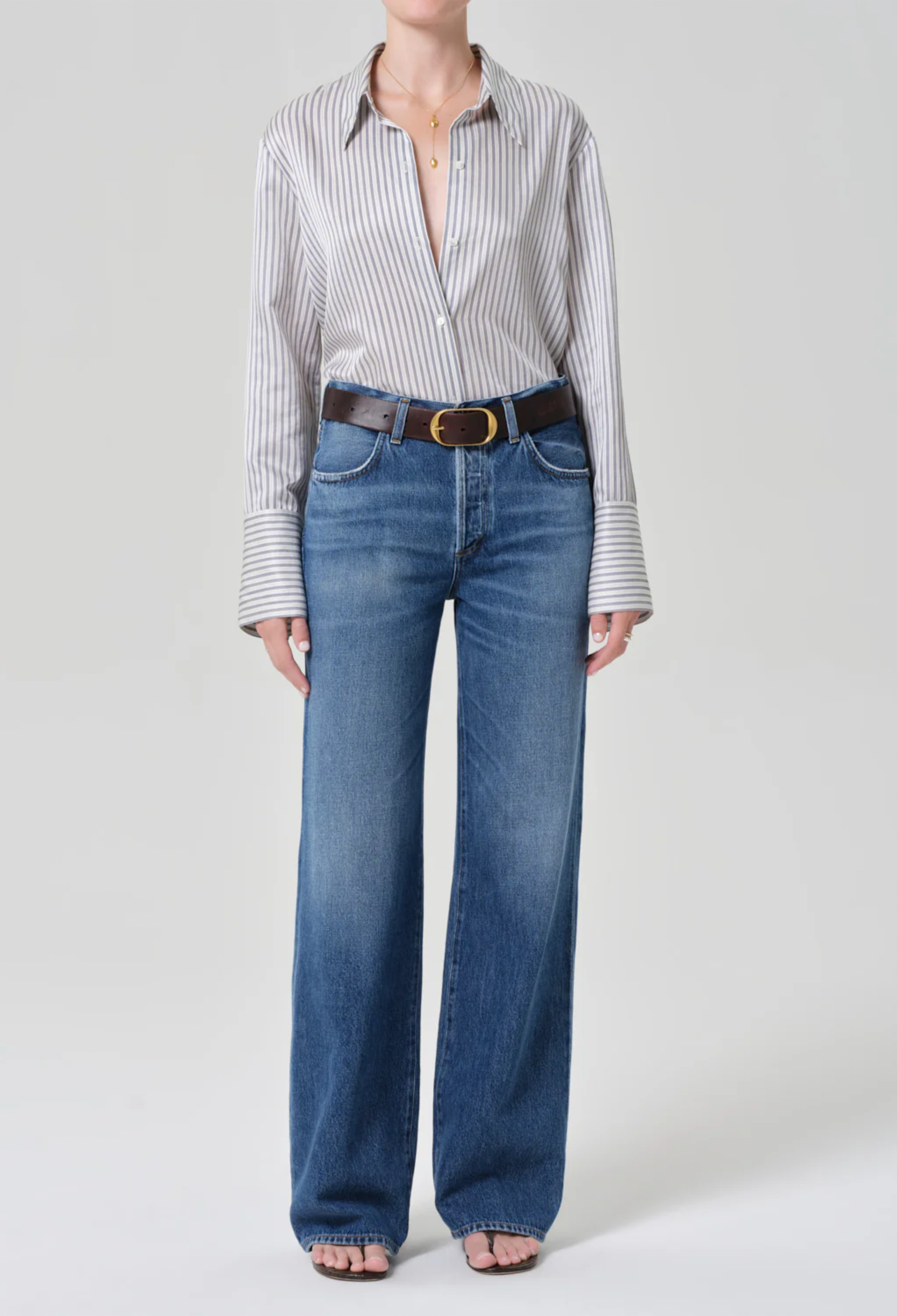 Person wearing a striped shirt and blue jeans on a white background