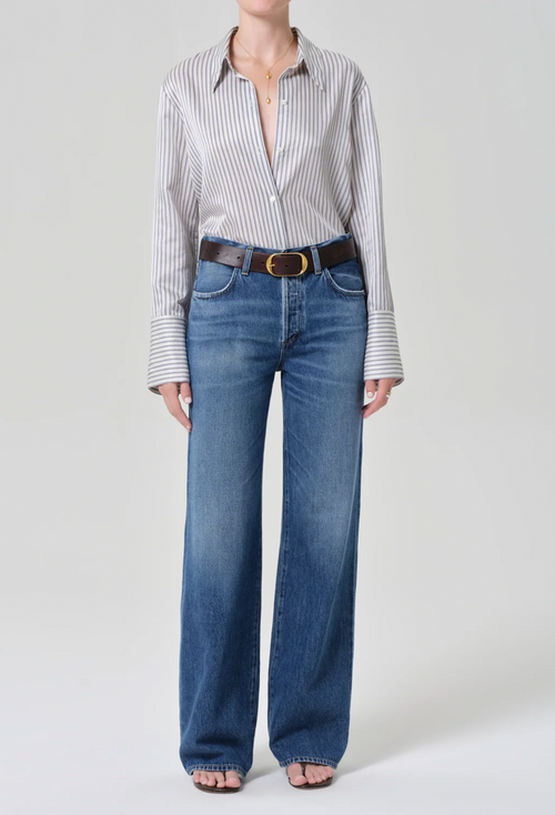 Person wearing a striped shirt and blue jeans on a white background