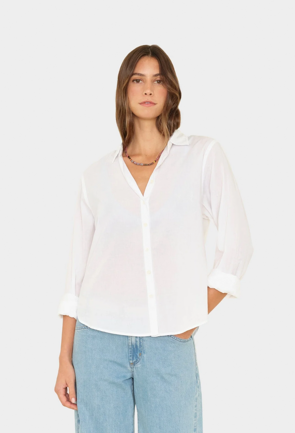Woman wearing a white blouse and light blue jeans on a white background