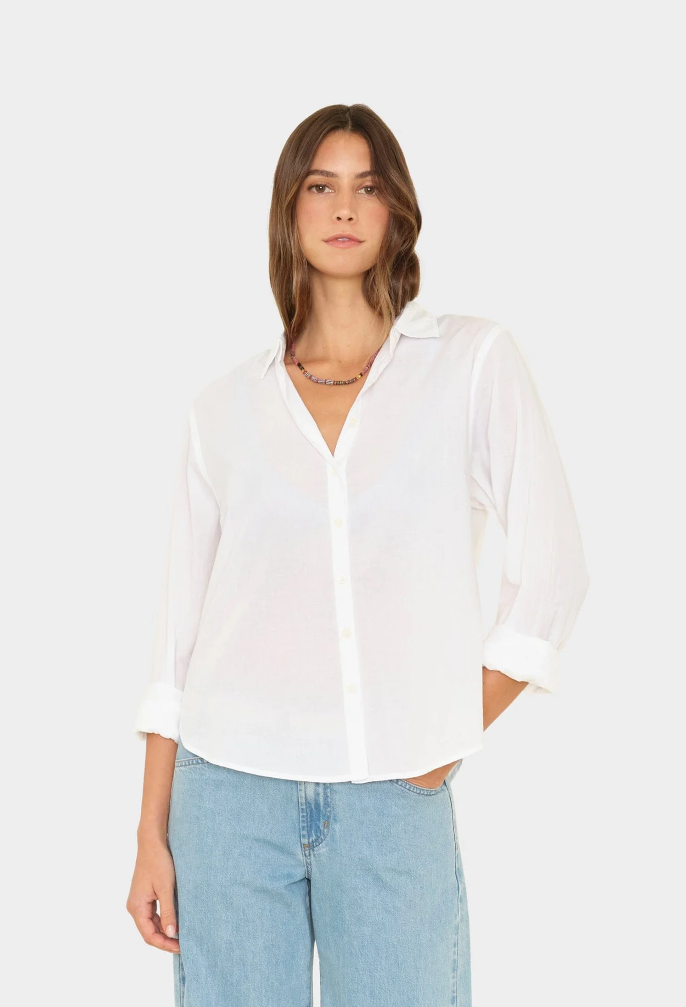 Woman wearing a white blouse and light blue jeans on a white background