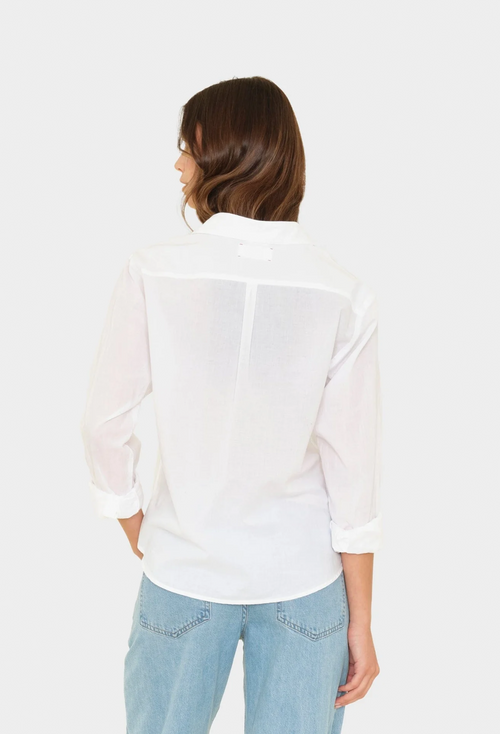 Woman wearing a white blouse and light blue jeans on a white background