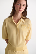 Woman wearing a yellow knit polo shirt on a white background