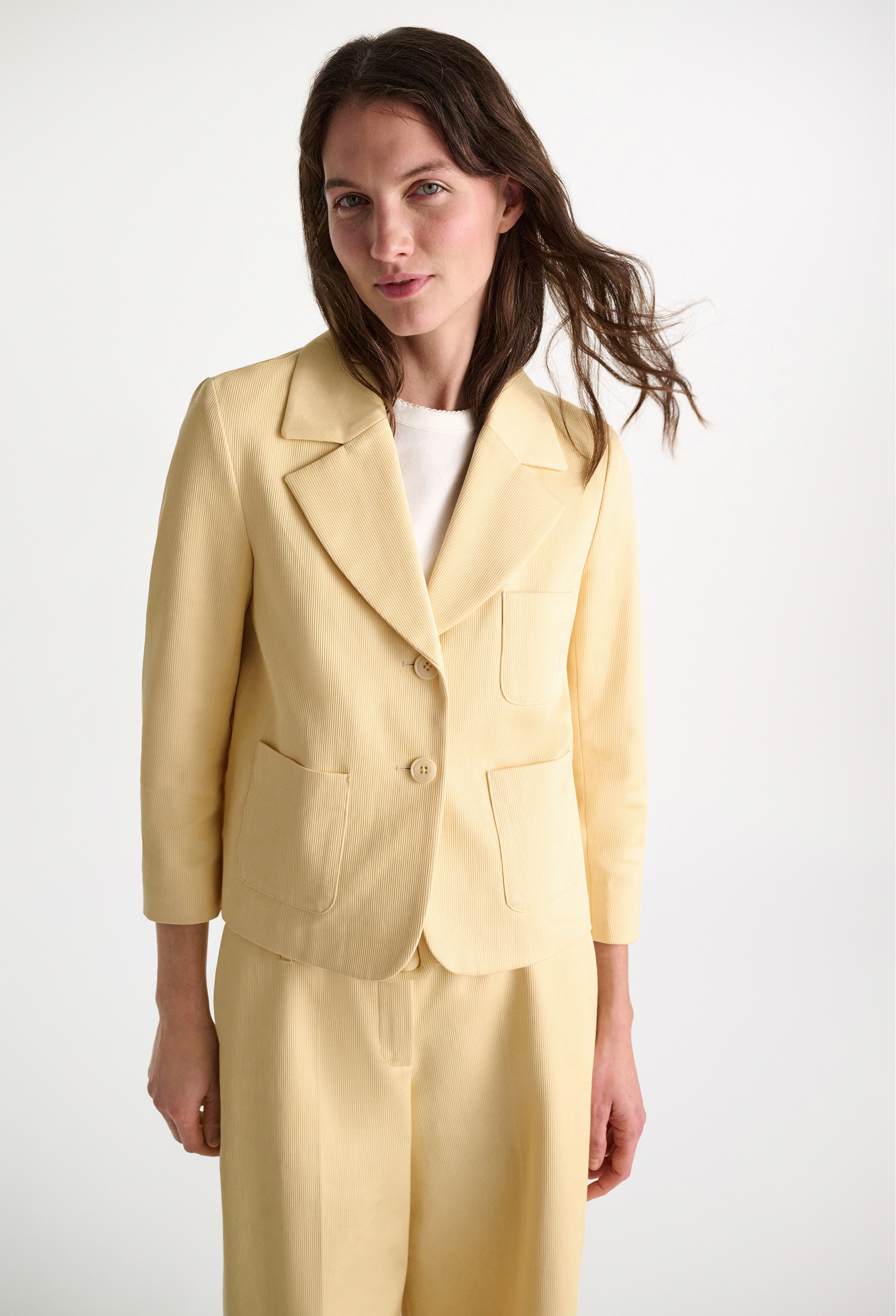 Woman wearing a light yellow suit against a white background