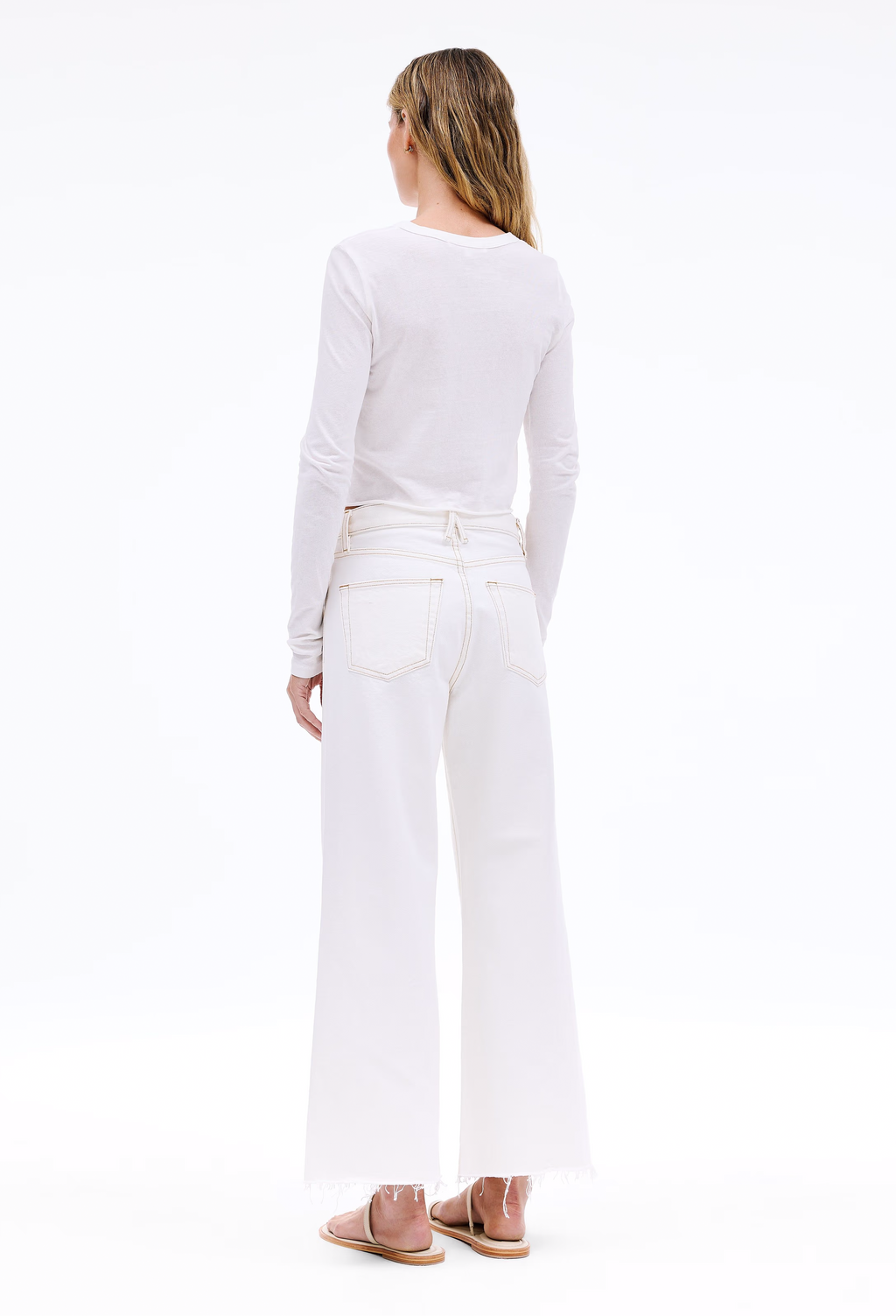 Person wearing a white long-sleeve top and white pants on a white background