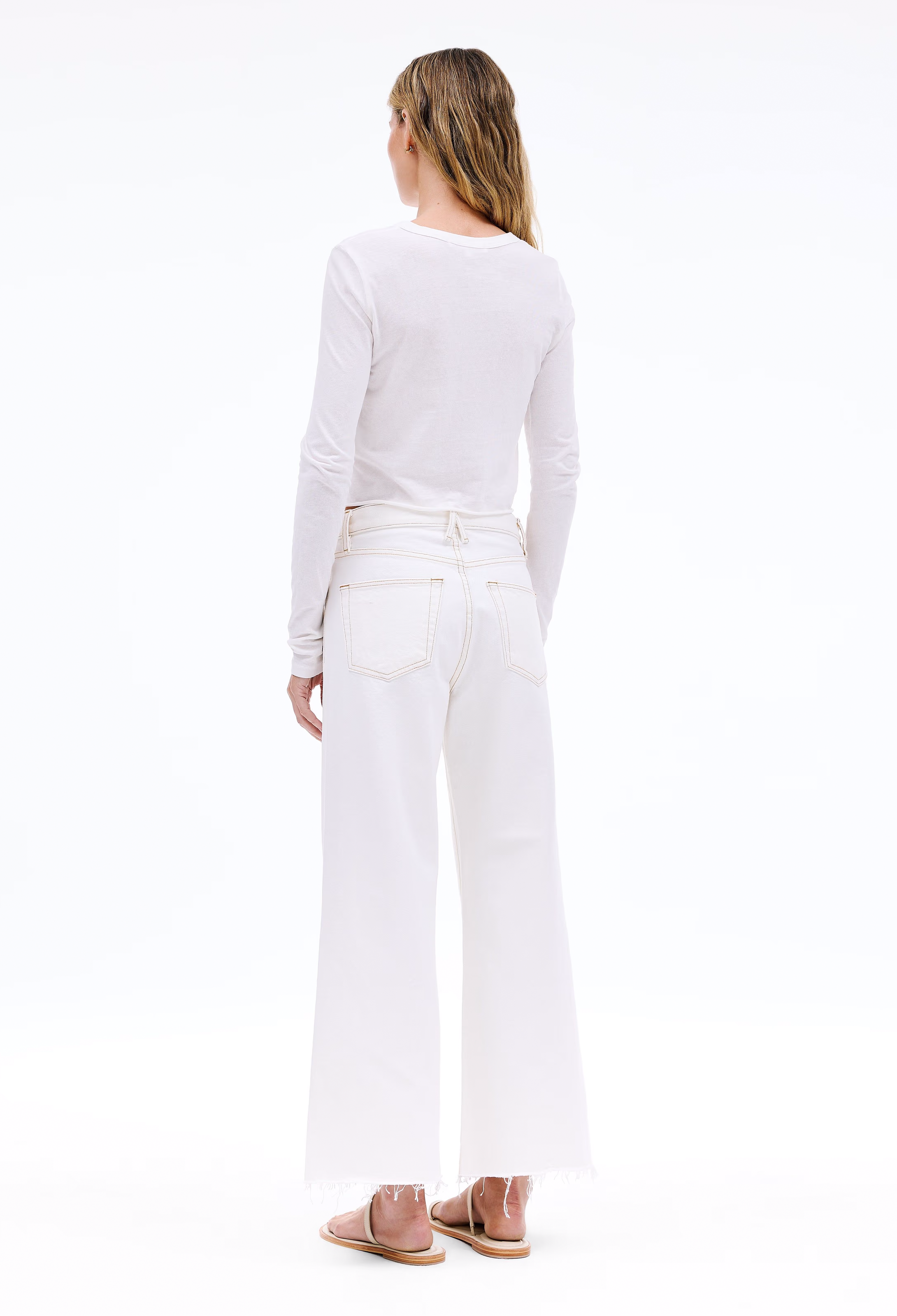 Person wearing a white long-sleeve top and white pants on a white background