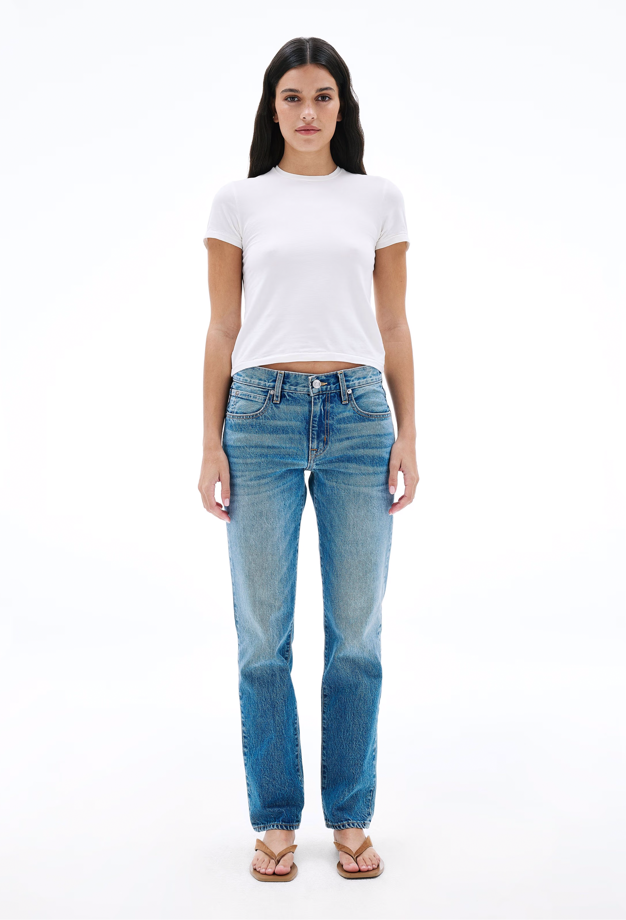 Woman wearing a white t-shirt and blue jeans on a white background