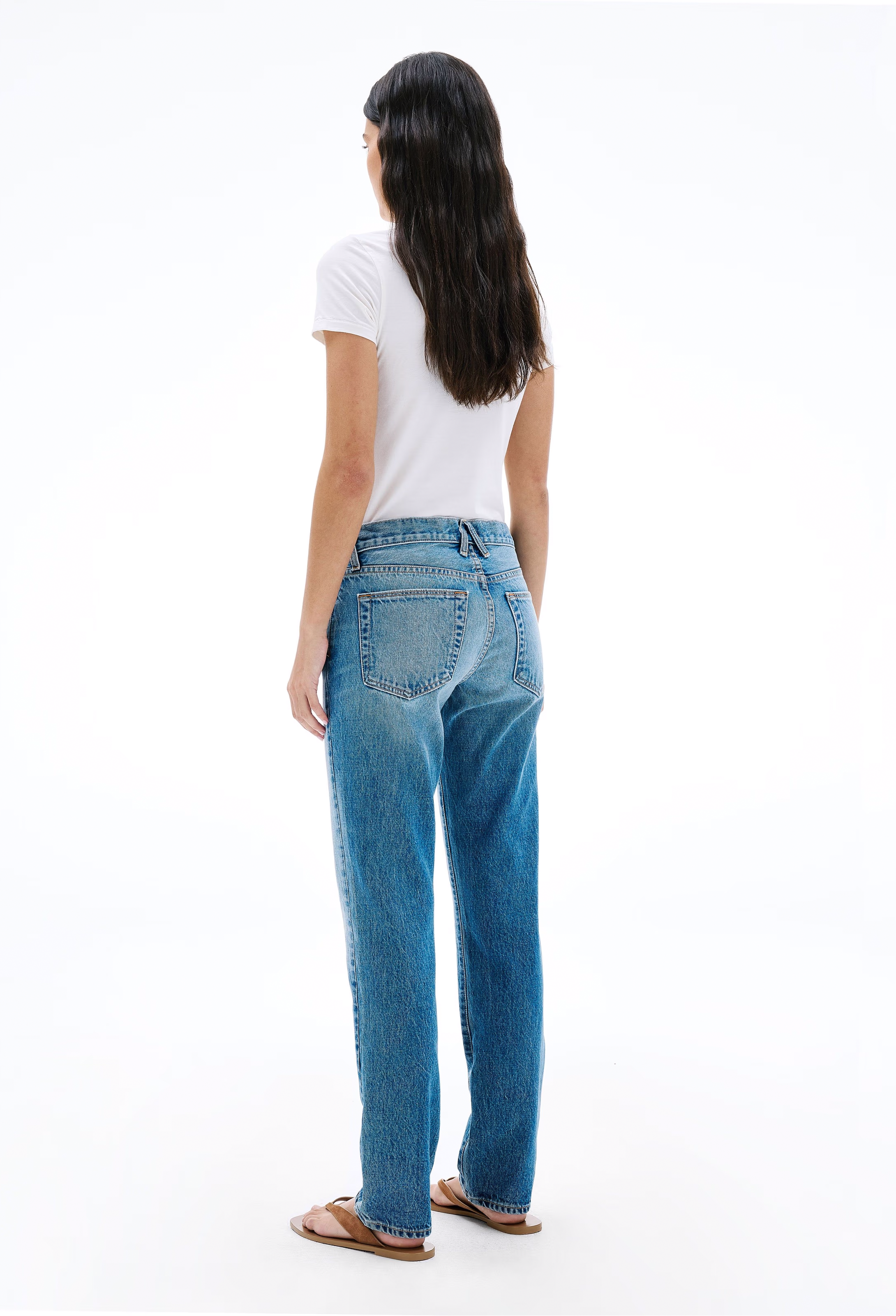 Person wearing blue jeans and a white shirt on a white background