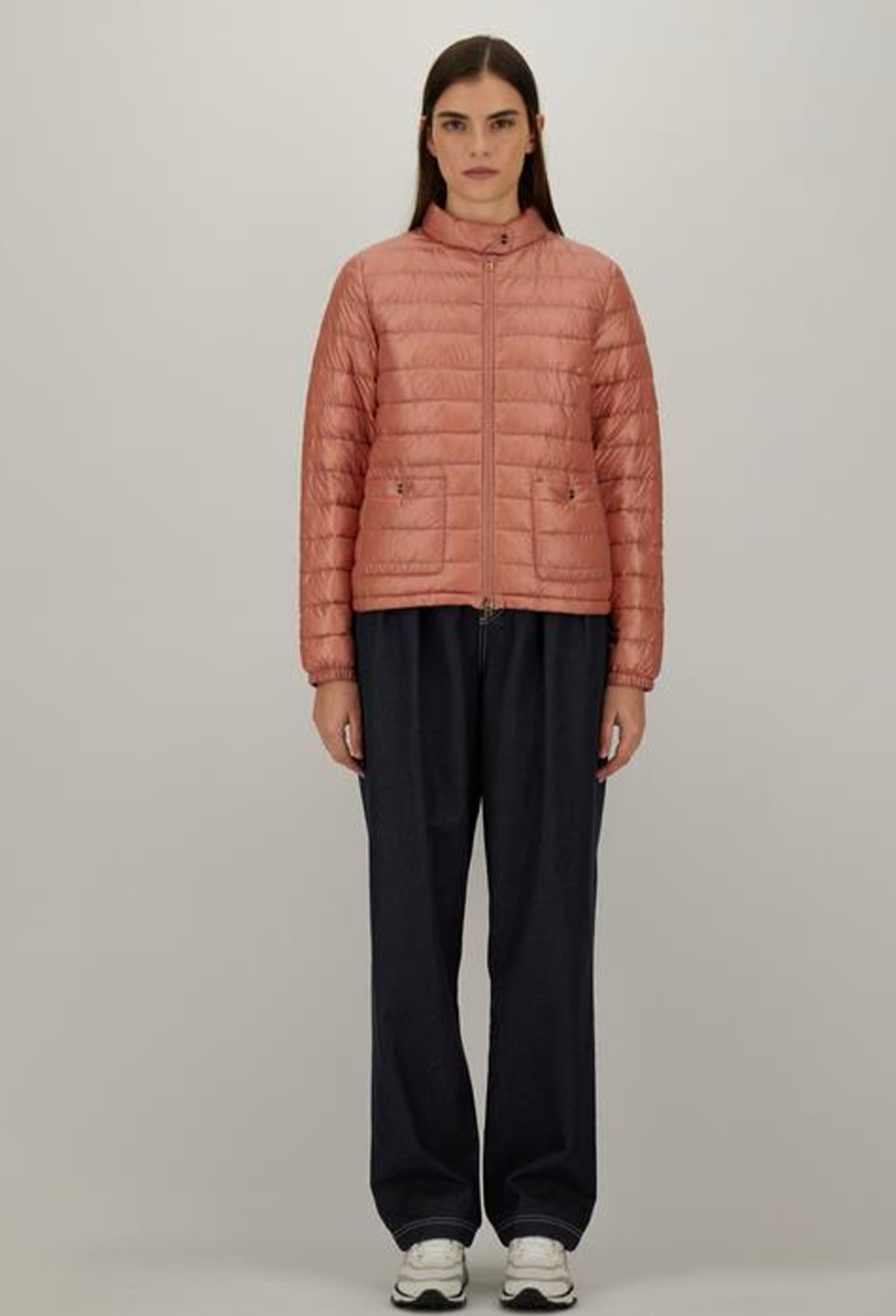 Person wearing a pink quilted jacket on a plain background