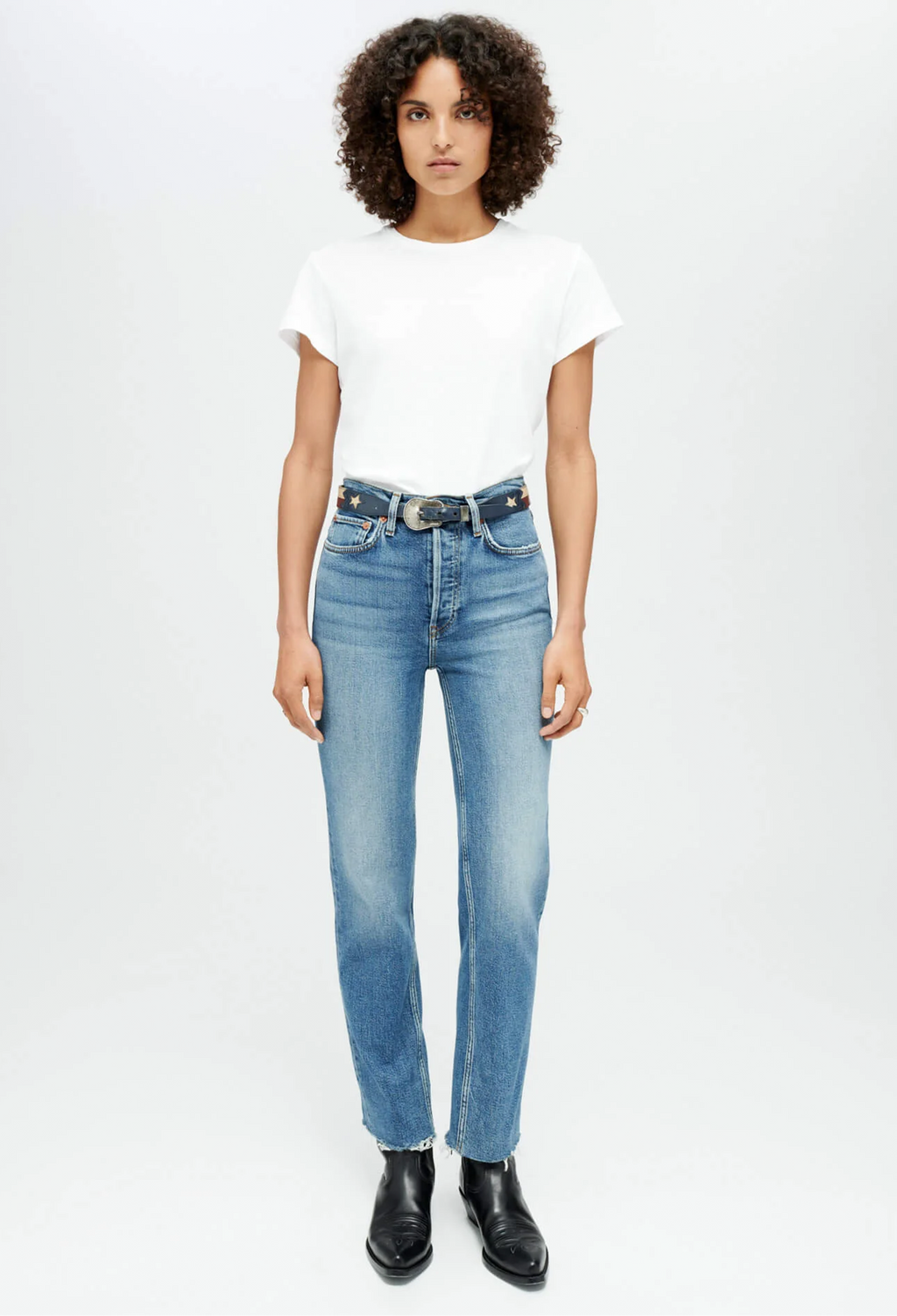 Woman wearing a white t-shirt and blue jeans on a white background