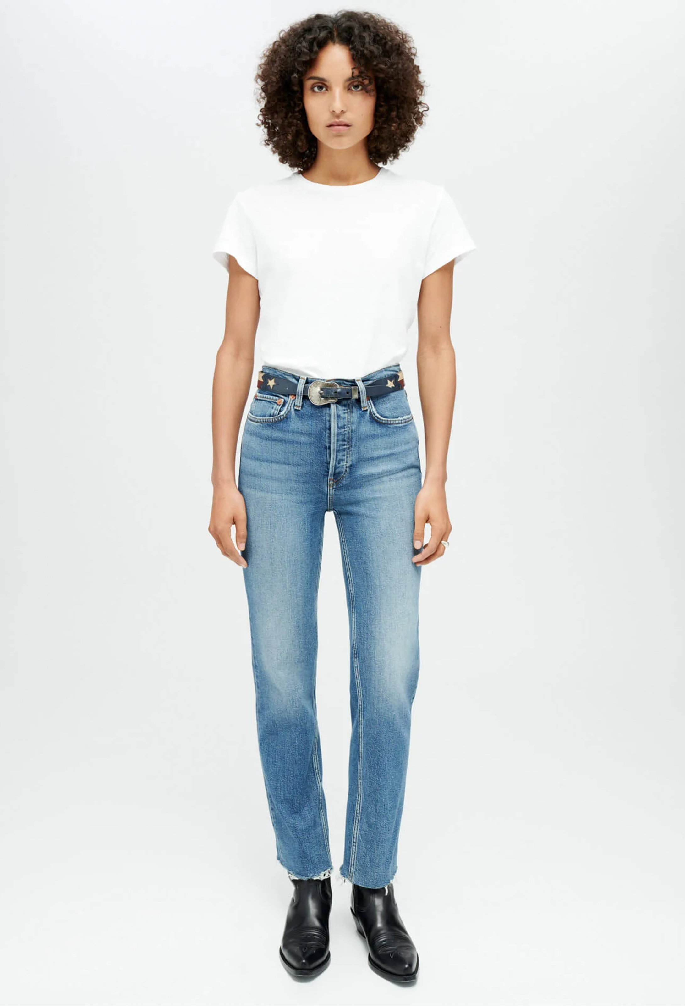 Woman wearing a white t-shirt and blue jeans on a white background