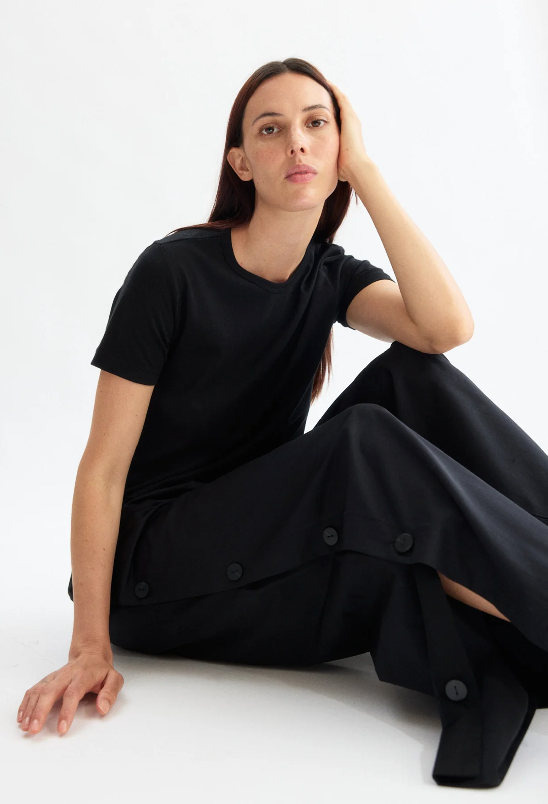 Woman wearing a black outfit sitting on a white background