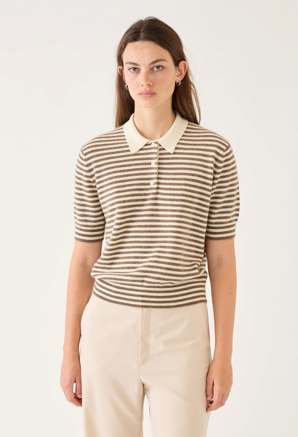 Woman wearing a striped shirt with a white collar against a plain background
