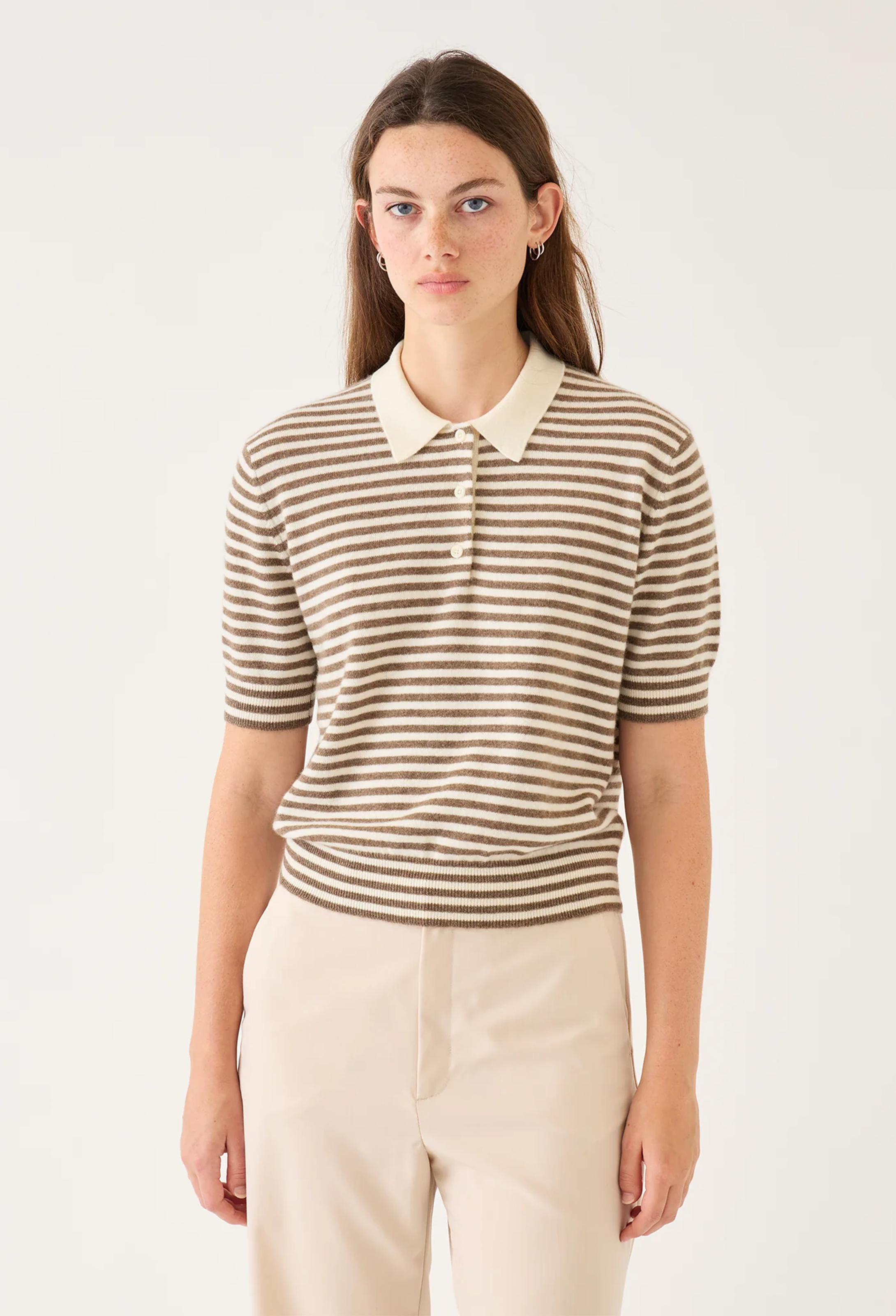 Woman wearing a striped shirt with a white collar against a plain background