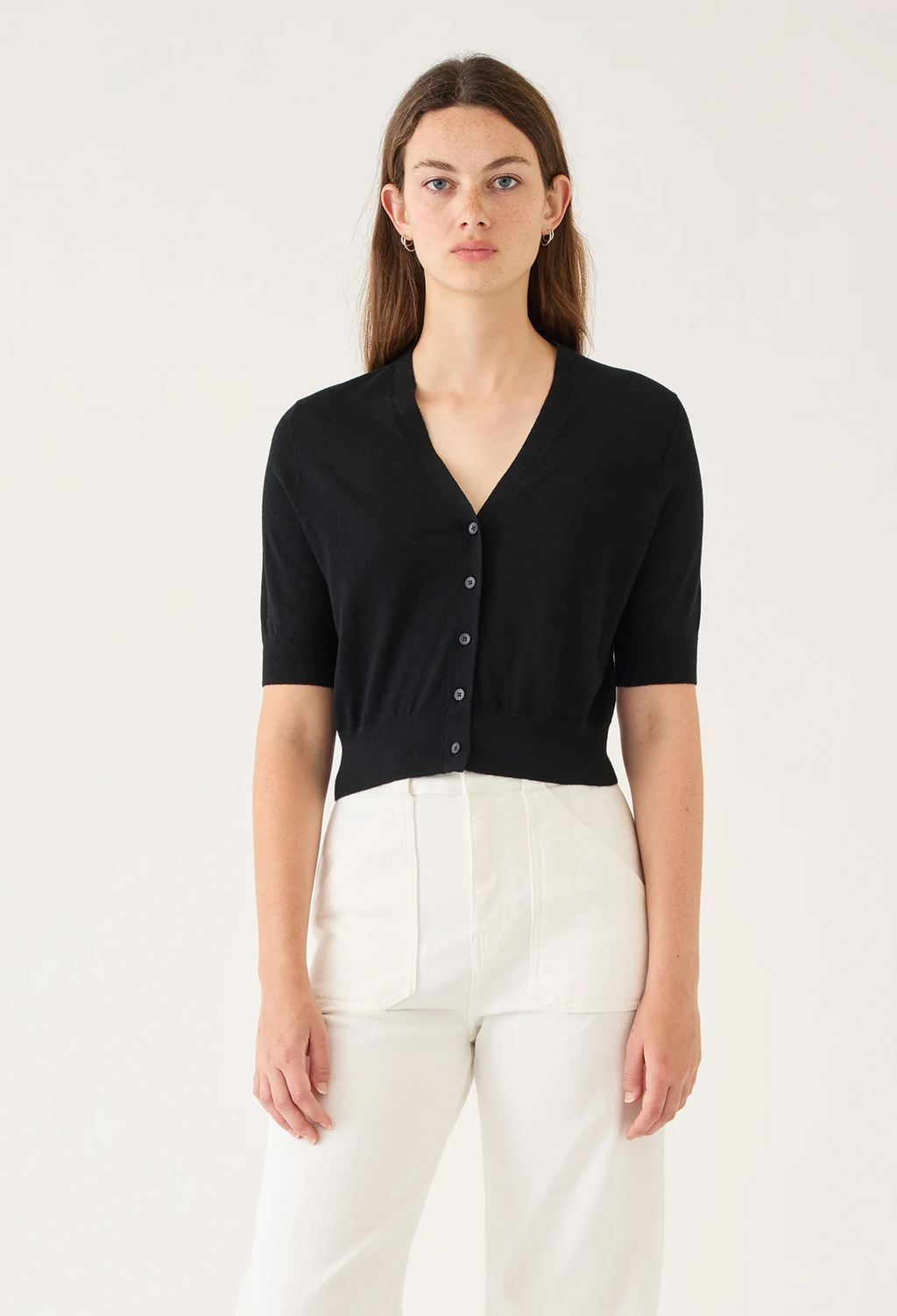 Woman wearing a black short-sleeve cardigan over a white top on a white background