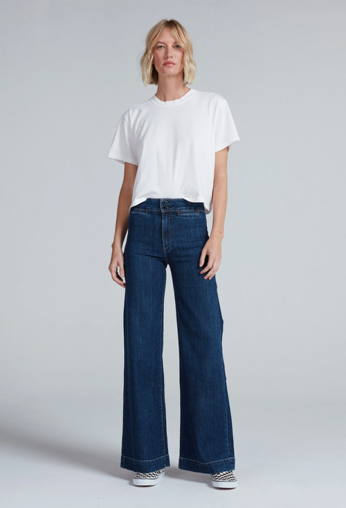 a model wearing a white tee and wide leg dark jeans on a white background