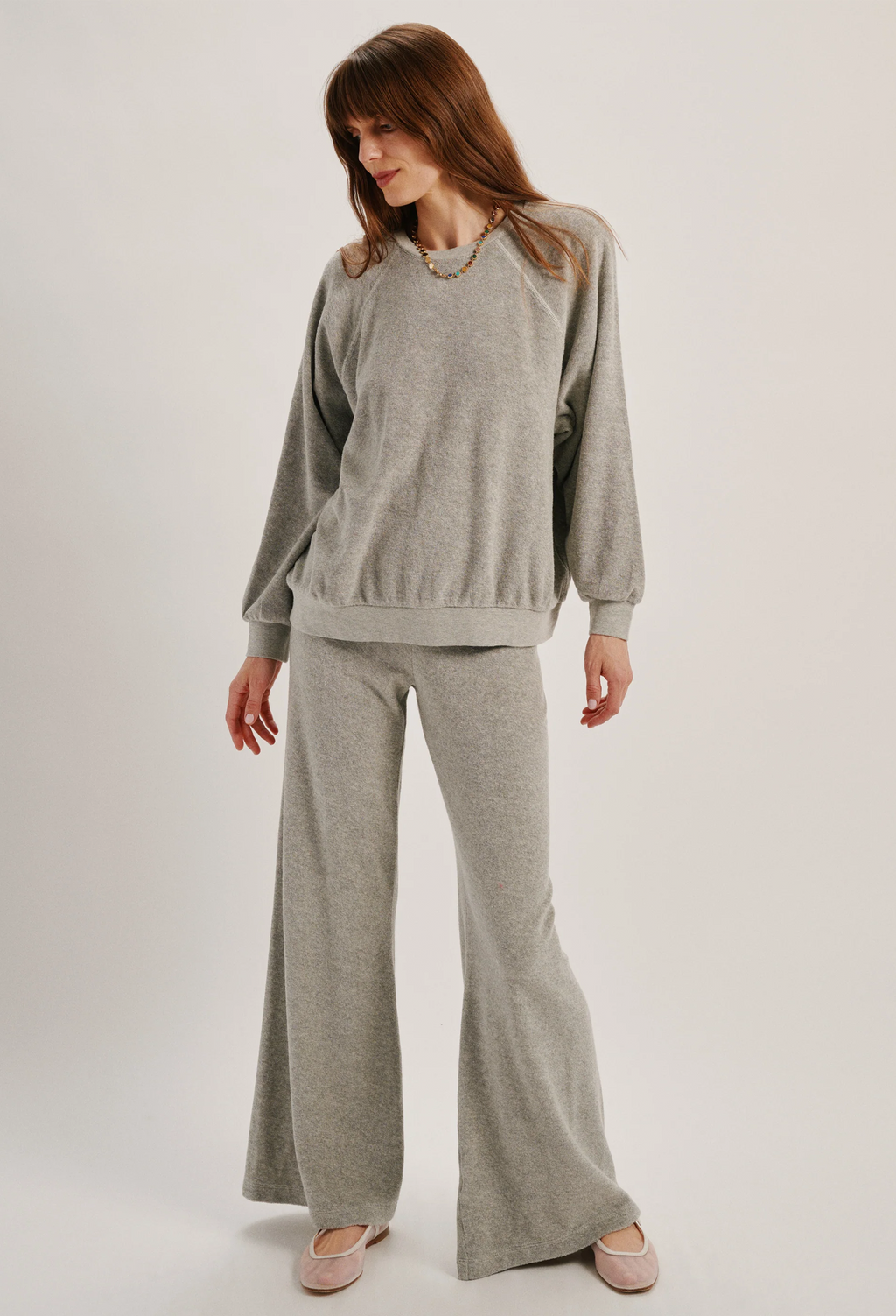 Woman wearing a gray sweater and pants set on a white background