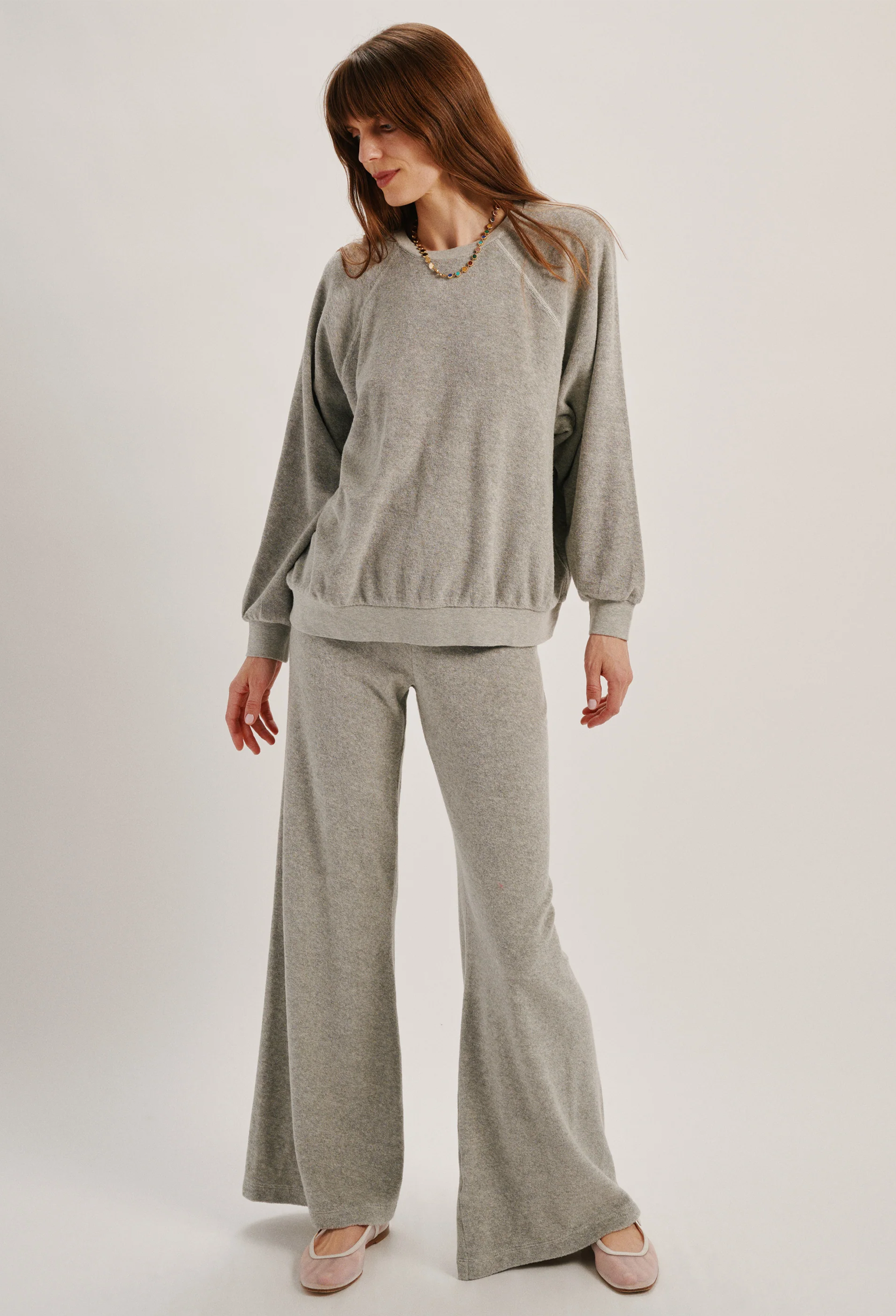 Woman wearing a gray sweater and pants set on a white background