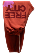 Orange sweatpants with 'FREE CITY' text on a white background