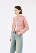 Person wearing a pink floral jacket and light blue jeans on a white background