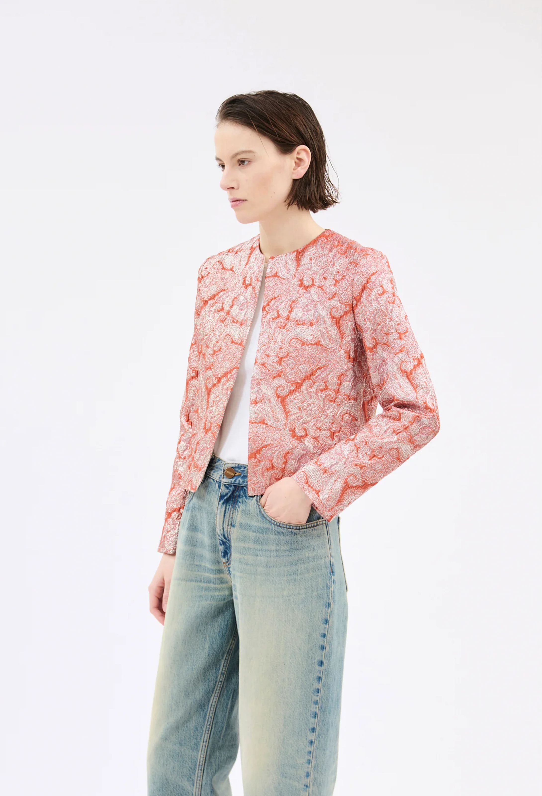 Person wearing a pink floral jacket and light blue jeans on a white background