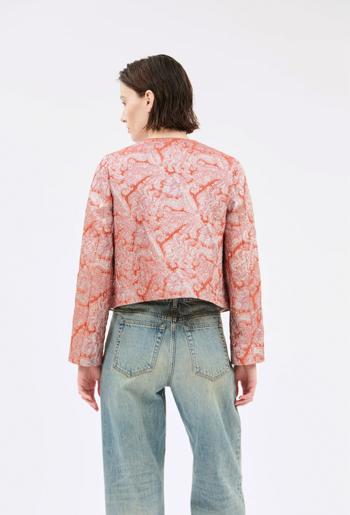 Person wearing a pink patterned top and light blue jeans on a white background