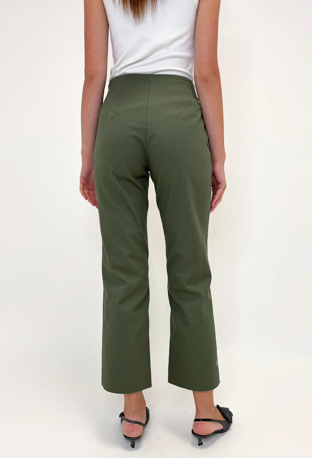 Person wearing green pants and a white top on a plain background