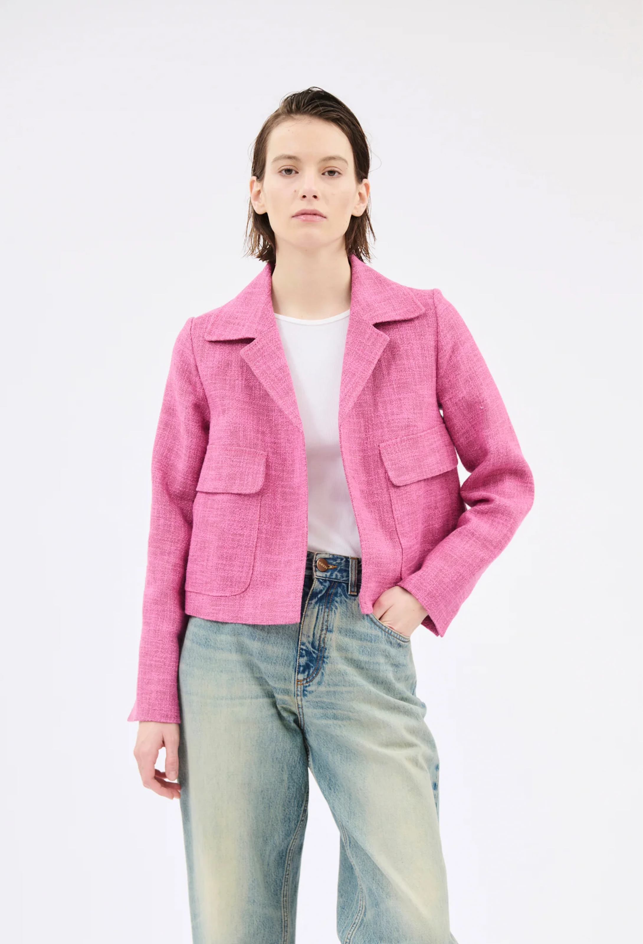 Person wearing a pink jacket and blue jeans on a white background