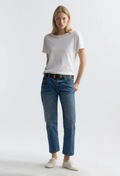 Woman wearing a white t-shirt and blue jeans on a plain background