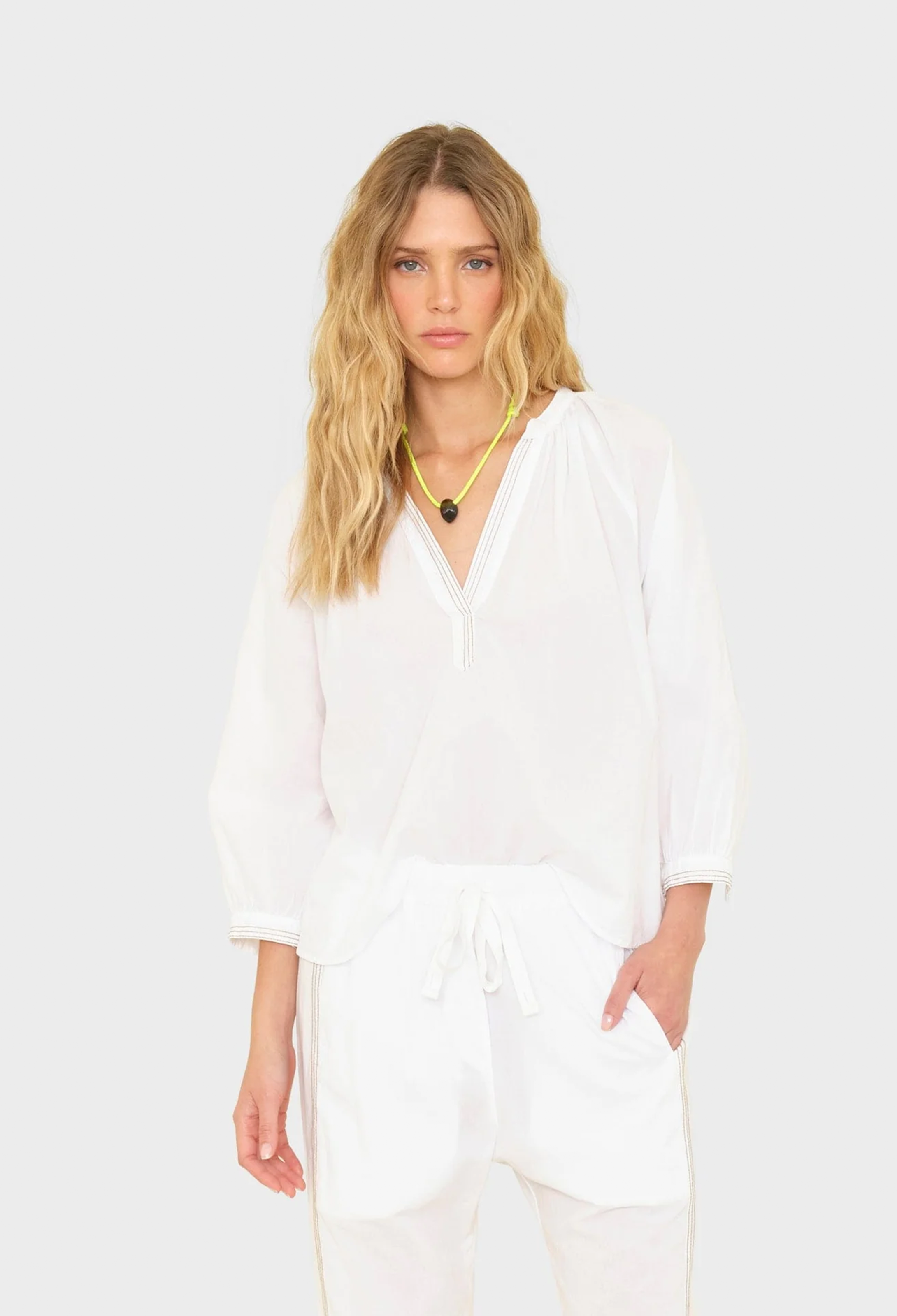 Woman wearing a white outfit on a plain background