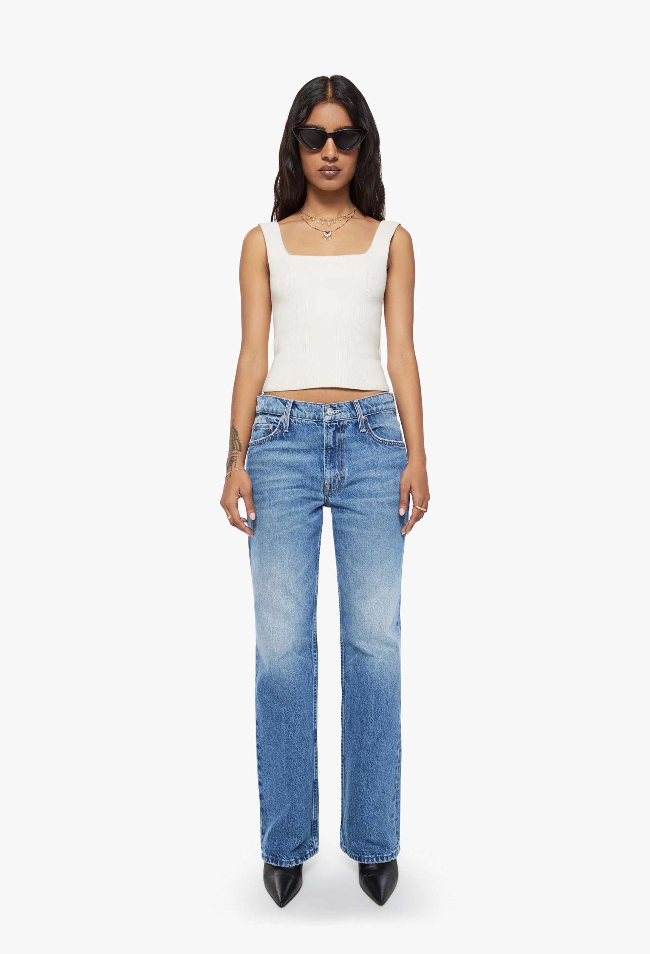 Woman wearing a white top and blue jeans on a white background