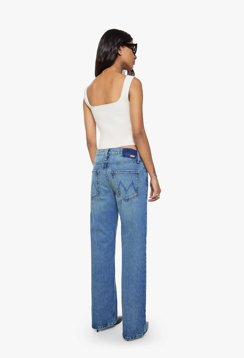 Woman wearing blue jeans and a white top on a white background