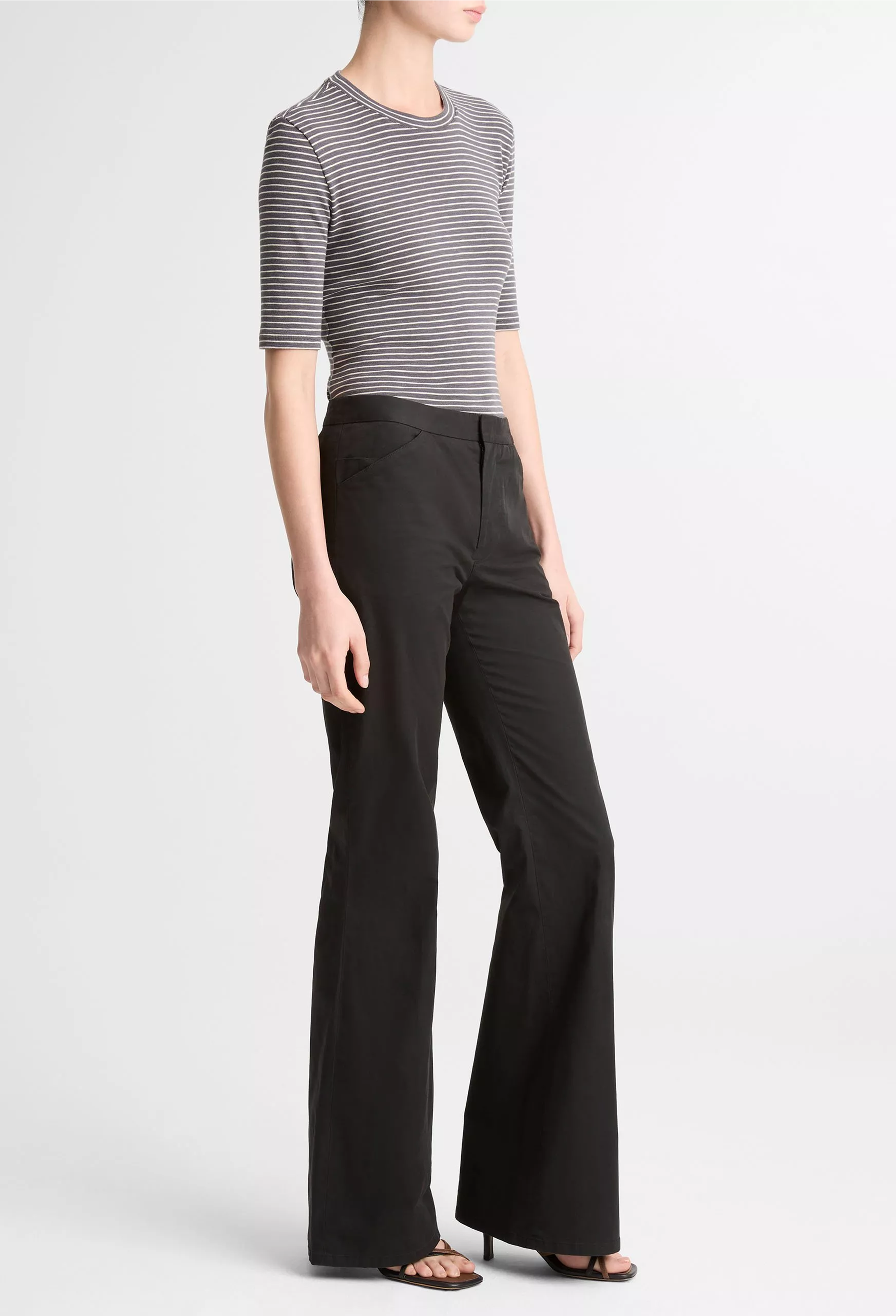 Person wearing a striped shirt and black wide-leg pants on a white background