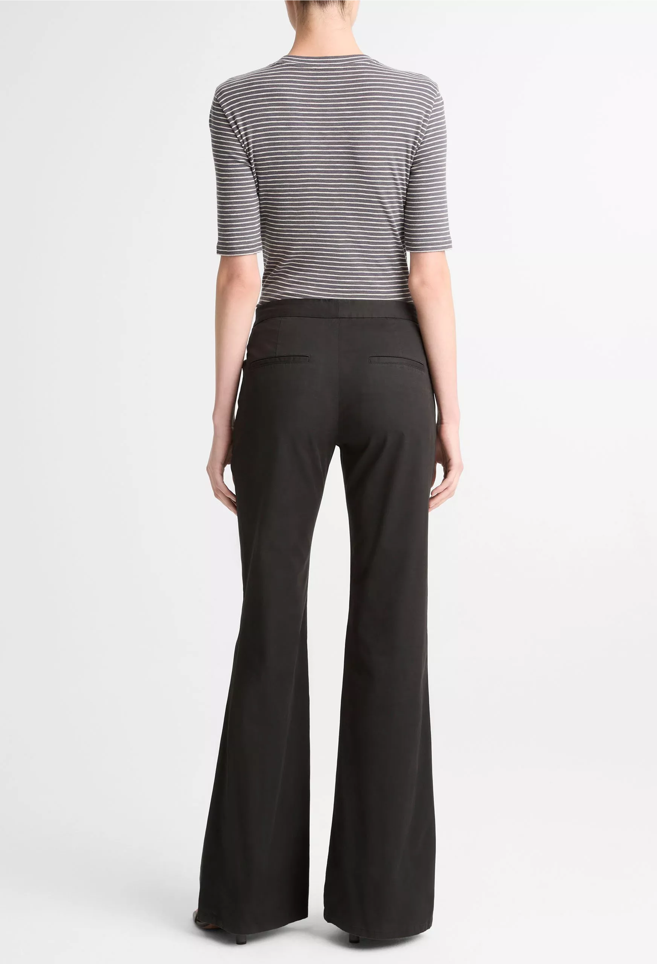 Person wearing a striped shirt and black flared pants on a white background