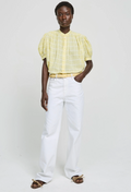 Person wearing a yellow blouse and white pants on a plain background