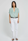 Woman wearing a green striped shirt and white pants on a plain background