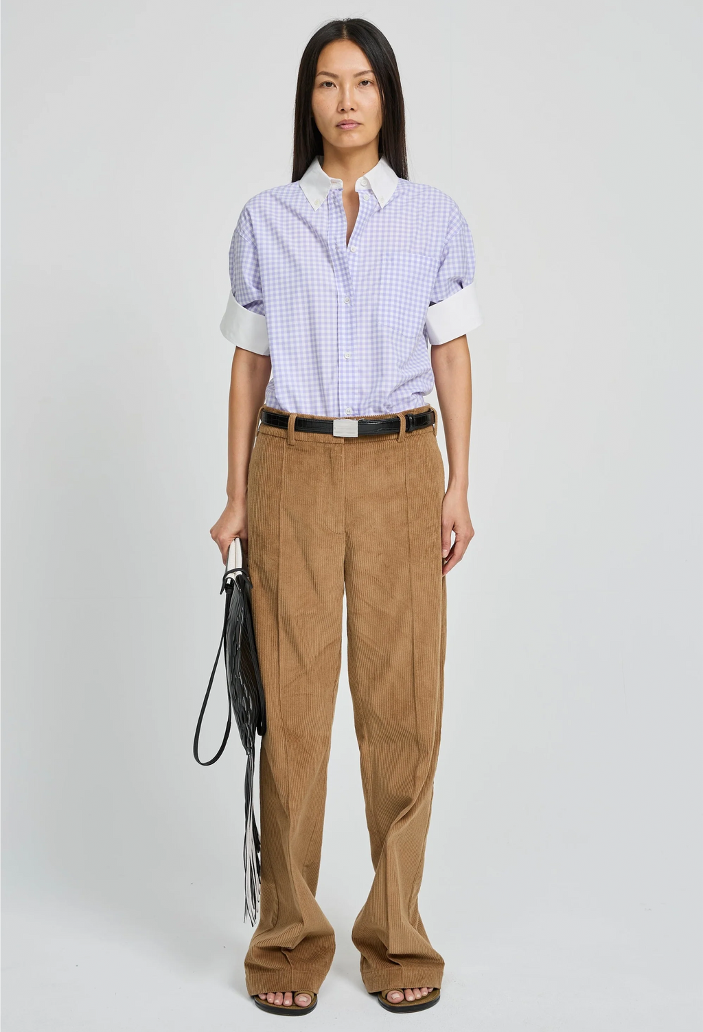 Woman wearing a checkered shirt and brown pants on a white background