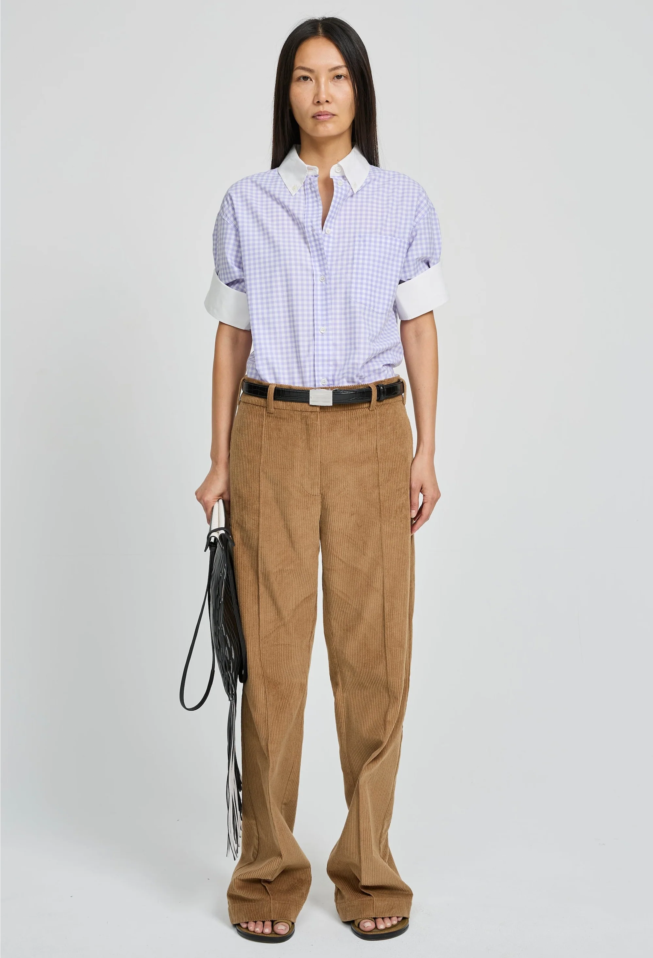 Woman wearing a checkered shirt and brown pants on a white background