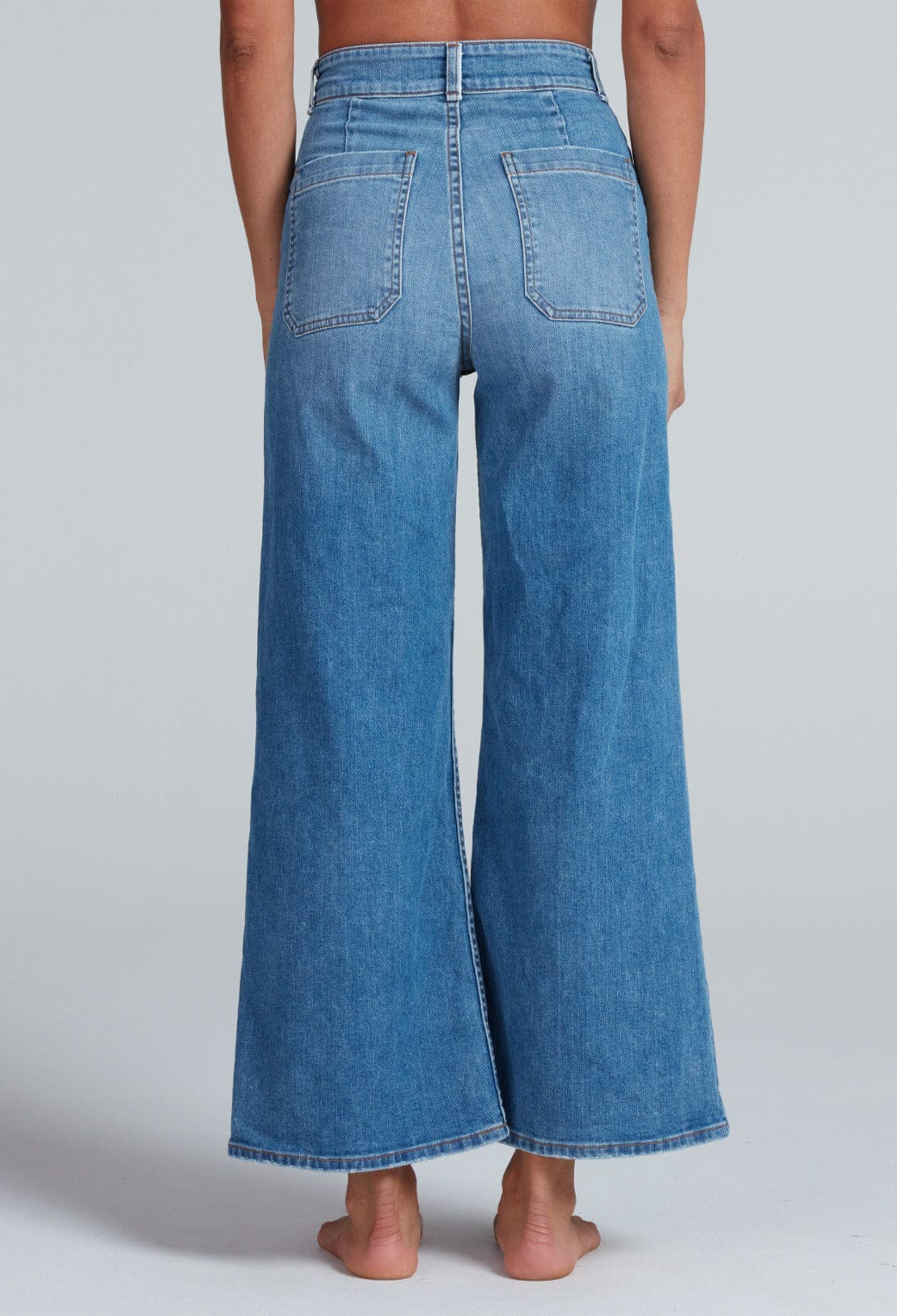 Blue denim wide-leg jeans worn by a person on a plain background
