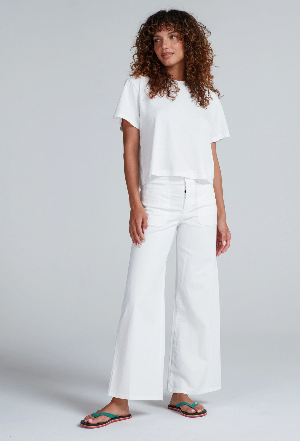 Person wearing a white t-shirt and wide-leg pants on a plain background